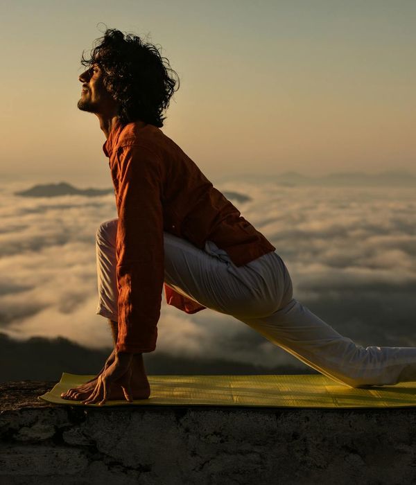 Silhouette of a person in a yoga warrior pose at sunrise.